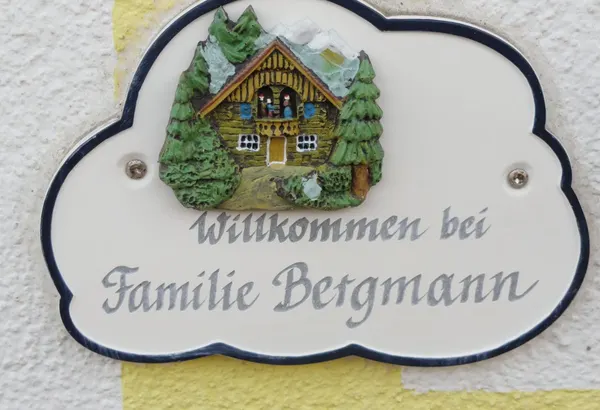 Keramikschild an der gelben Hauswand: Willkommen bei Familie Bergmann